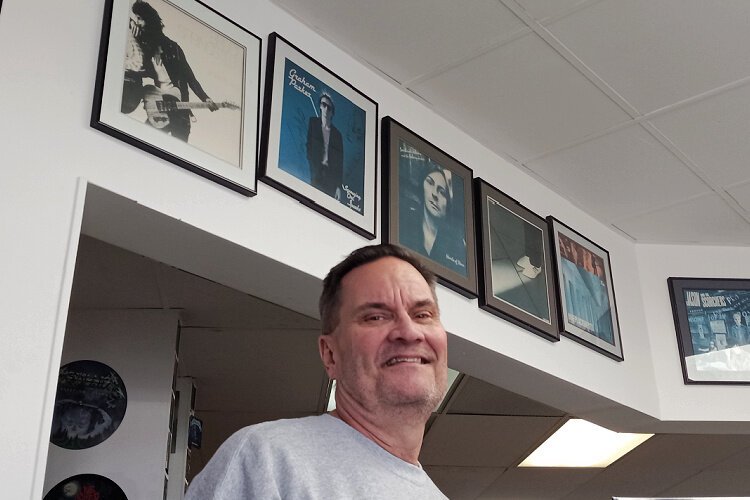 Phil Breen, who’s operated Phil’s Records at various locations since 1989, poses in front of his Wall of Fame that features his favorite 10 albums – Bruce Springsteen’s Born to Run tops the list.
