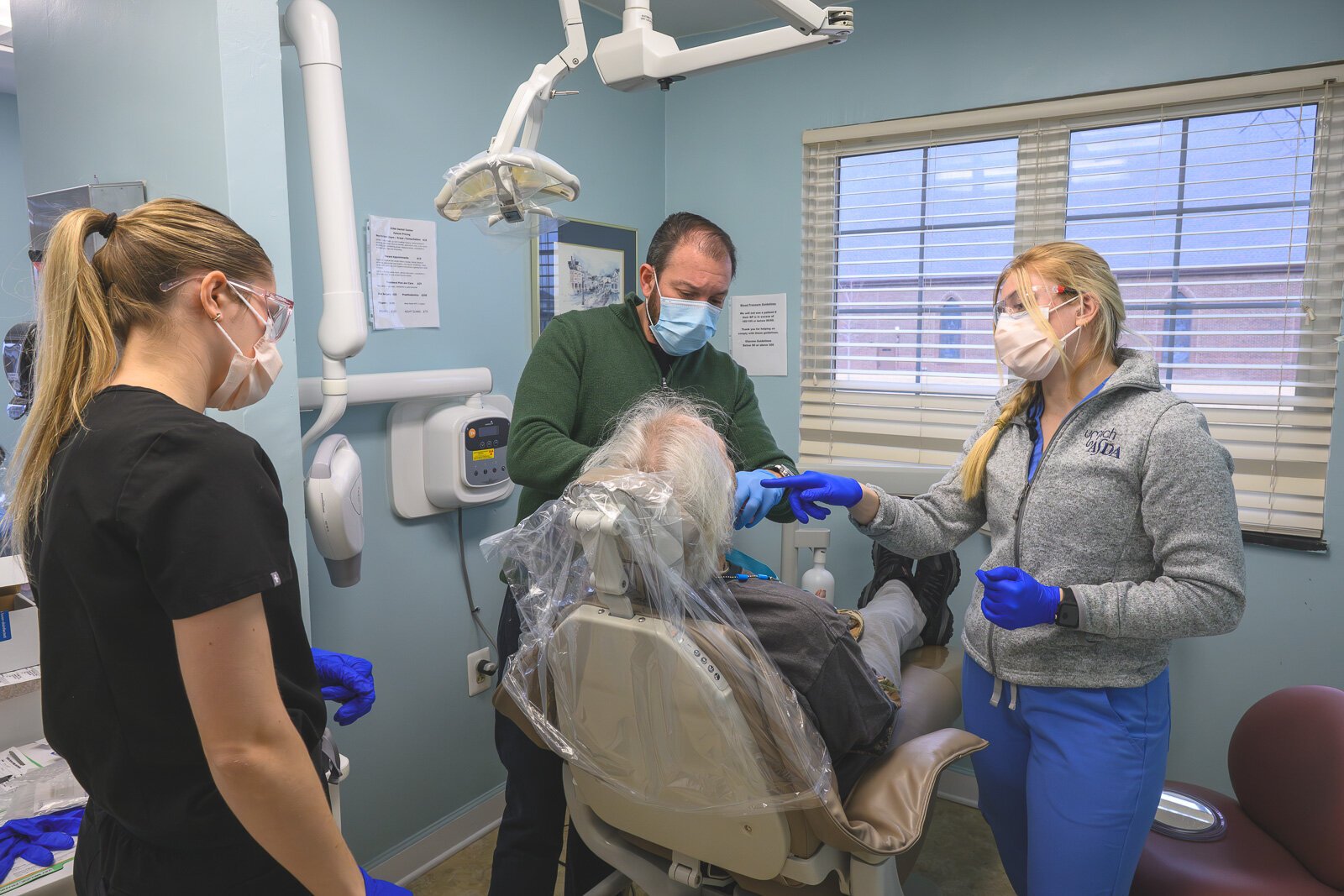 Dental intern Sarah Cawthon, Dr. Ken Marriott, and dental intern Rylee Miller treat a patient at VINA Community Dental Clinic in Brighton.